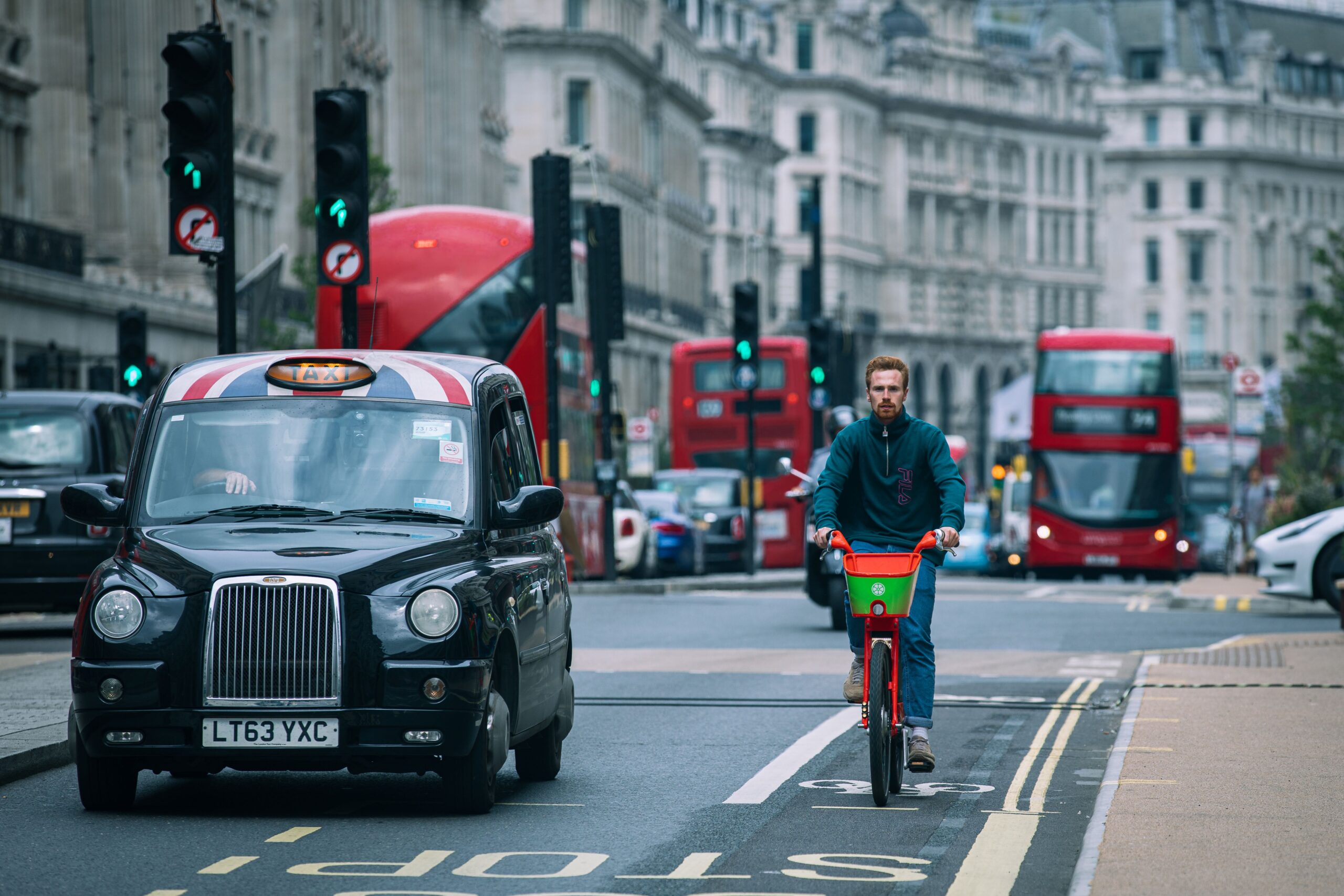 A cyclist riding amidst traffic in London's bustling streets.